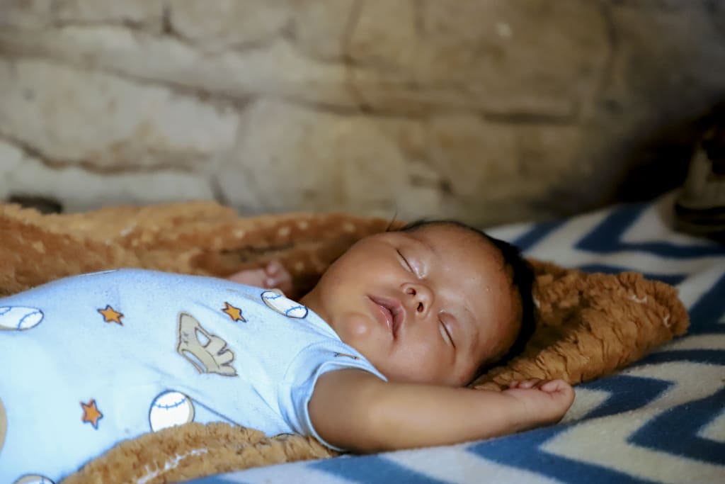 newborn baby in blue onesie sleeps