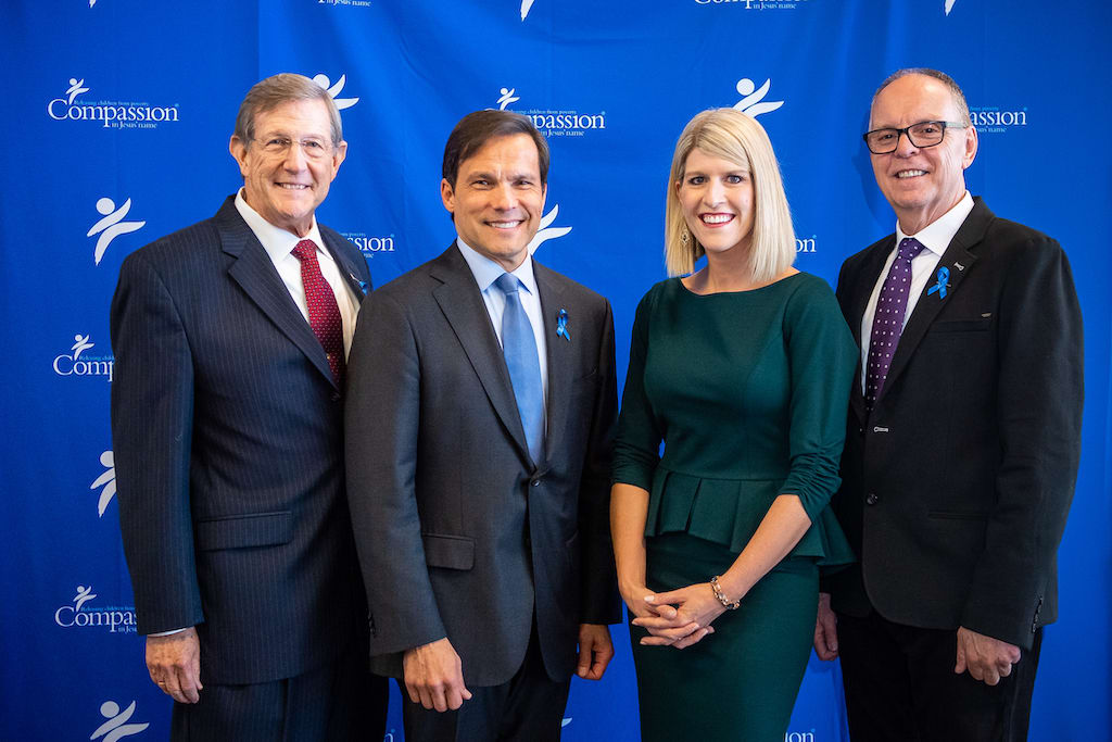 Dr. Wess Stafford, Santiago "Jimmy" Mellado, Allison Alley and Barry Slauenwhite pose in front of a blue Compassion backdrop.