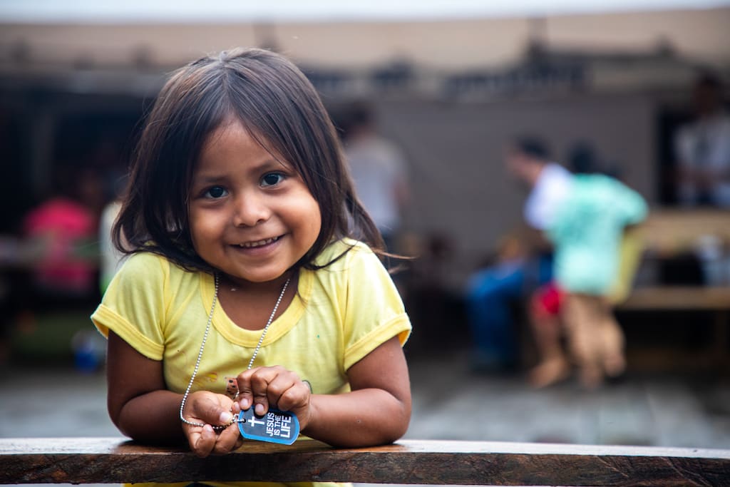 A girl in a yellow t-shirt smiles at the camera.