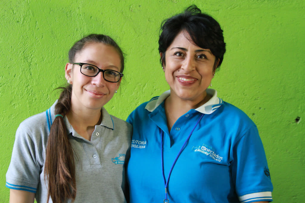 A young women stands next to a middle aged woman, her former mentor, and smiles at the camera
