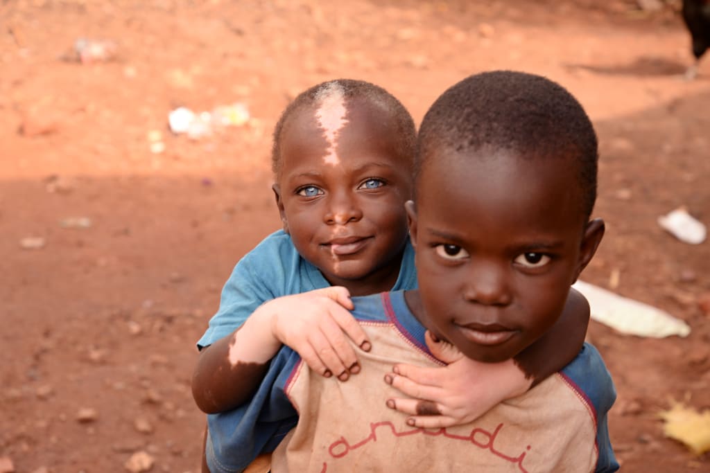 Shakul is on his best friend's back. He is smiling at the camera.