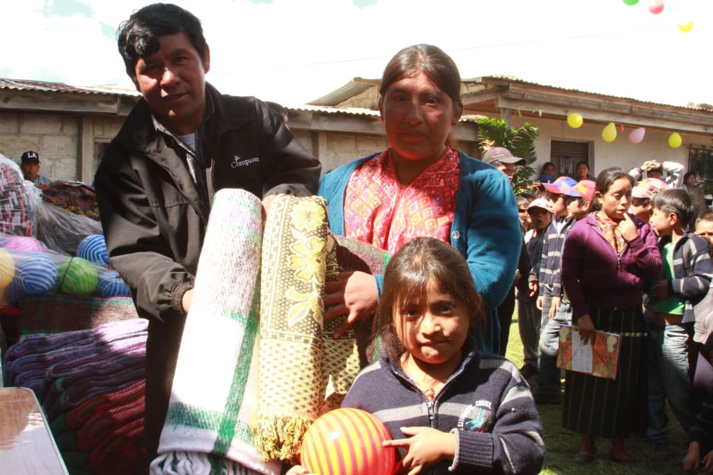 A girl smiles with her new gifts in hand from the Christmas party at project