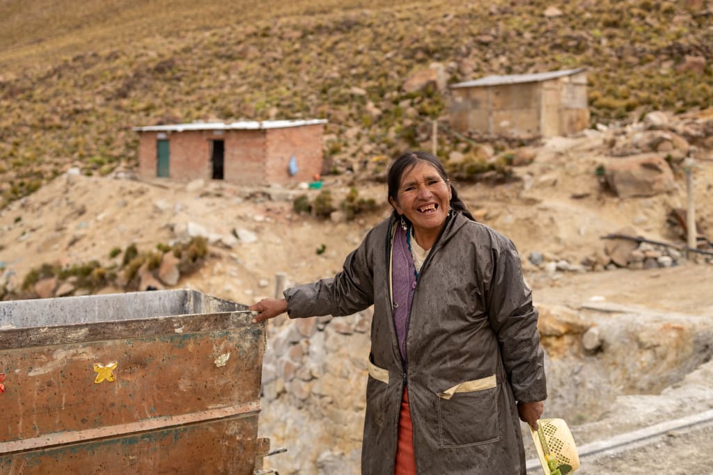 A woman is smiling as she stands in the mine where she works as a guard.