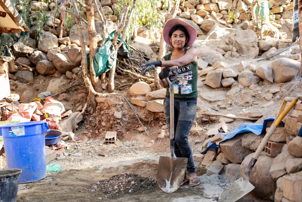 A young woman is standing at a worksite posing with a shovel.
