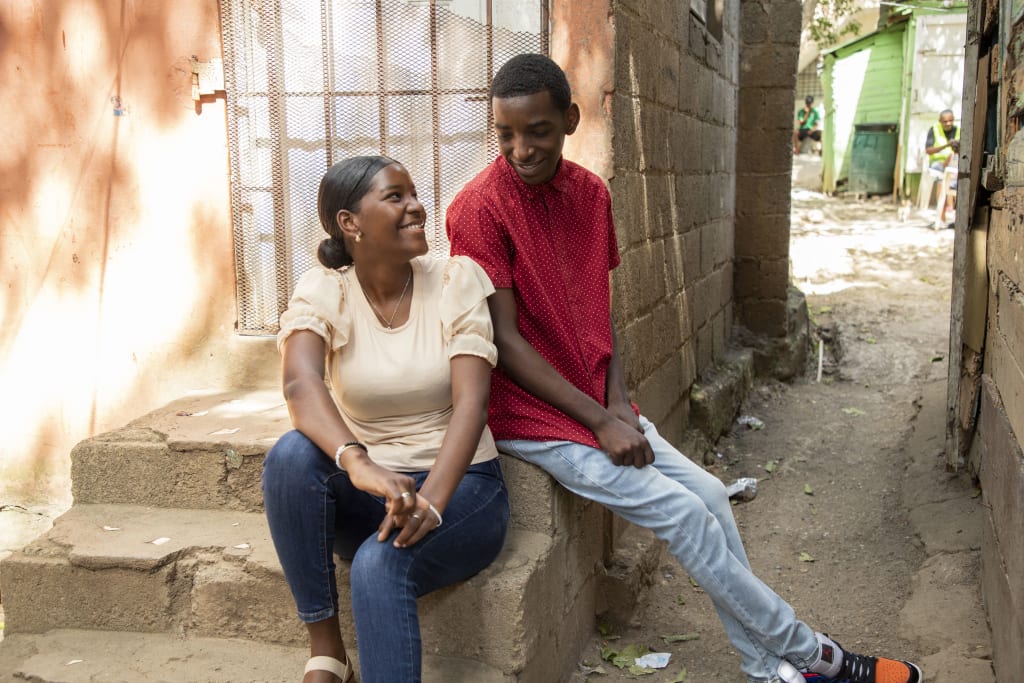 Daniel and Daniela are looking at each other and smiling. They are sitting on the steps outside a neighbour's house.