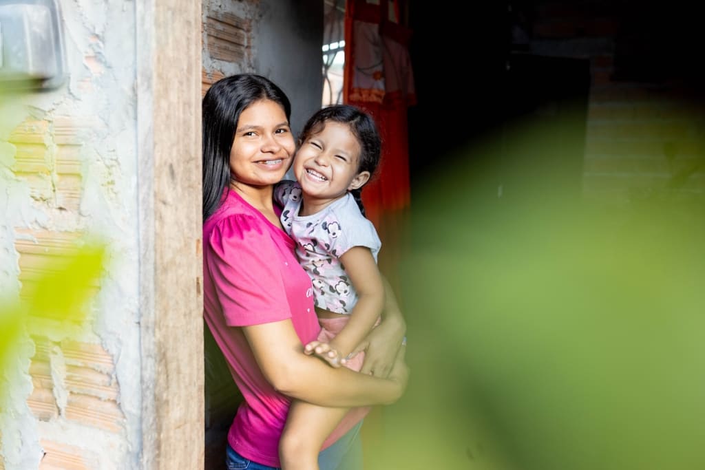 Gabriella poses for a picture in her doorway while holding her daughter, Dávilla.