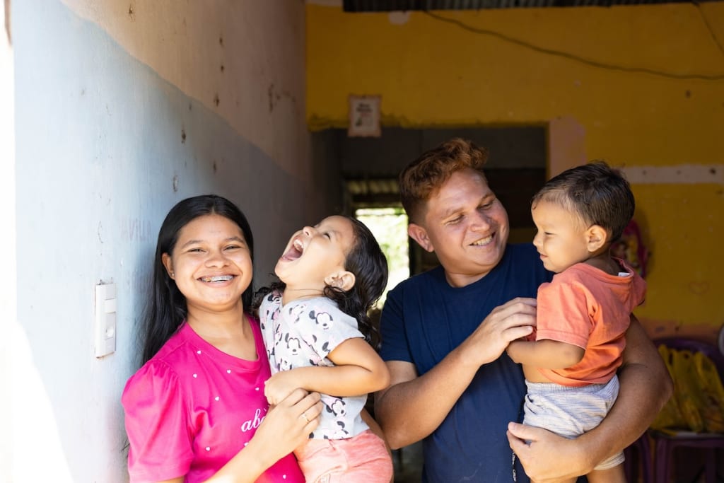 Gabriella and her husband, Bruno, are holding and playing with their children in their home.