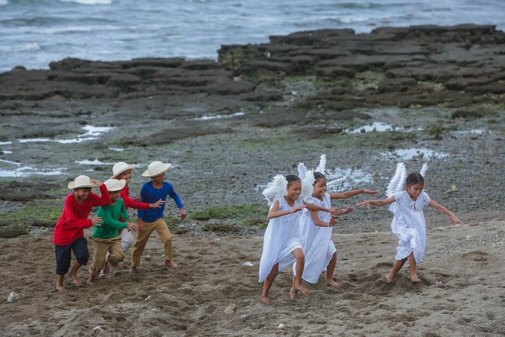 A group of boys dressed as shepherds run after a group of girls dressed as angels.