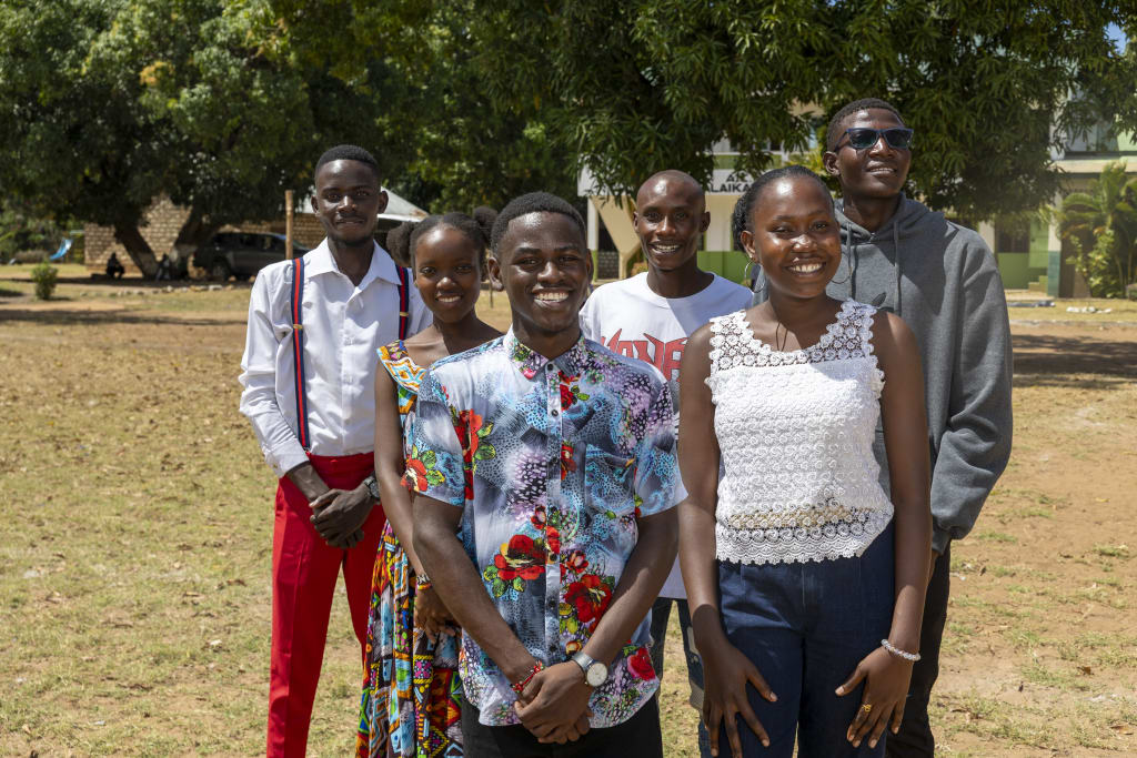 A group of six youth stand together and smile.