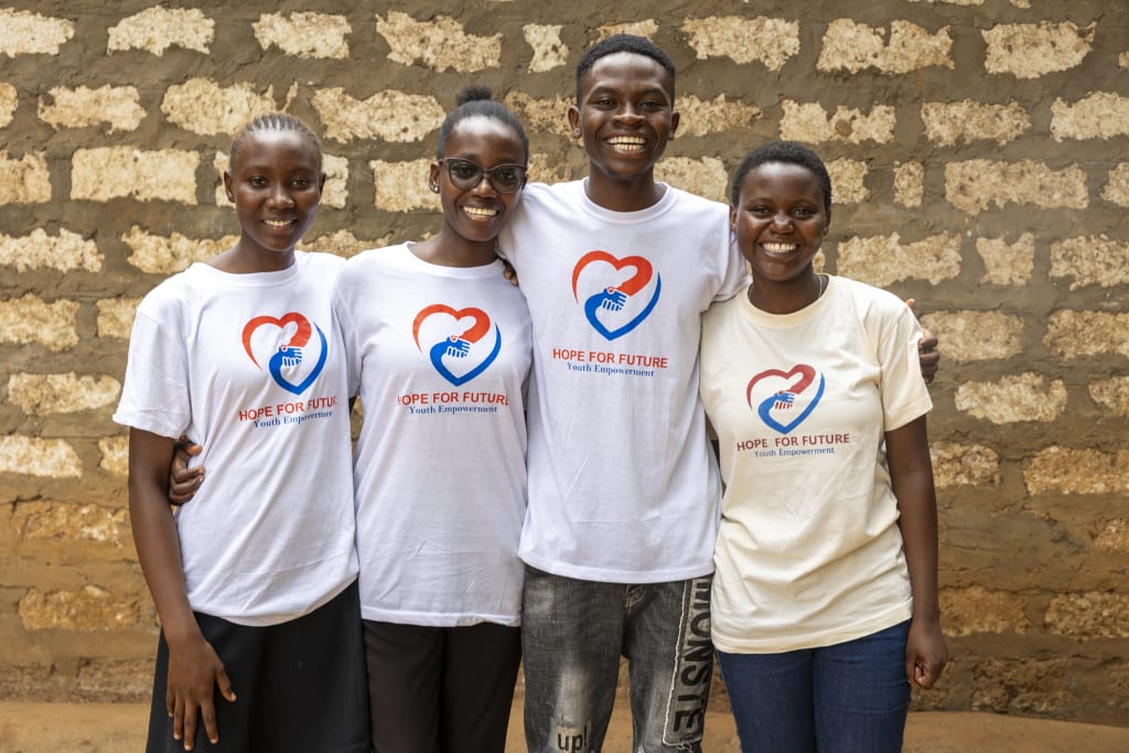 A group of youth stand in white t-shirts that read "Hope for Future, Youth Empowerment."