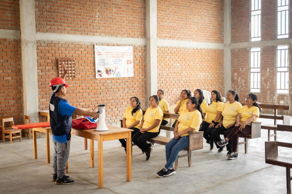 Staff from a Compassion centre in Peru sit on wooden benches, attending a training session on security during a natural disaster.