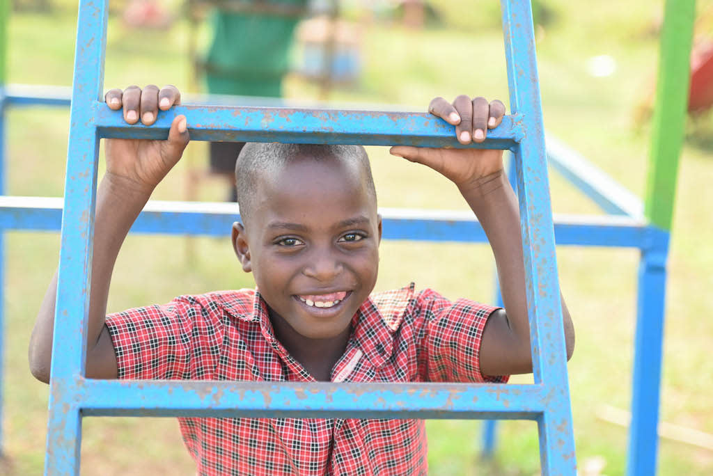 Samuel is smiling looking through a blue ladder.