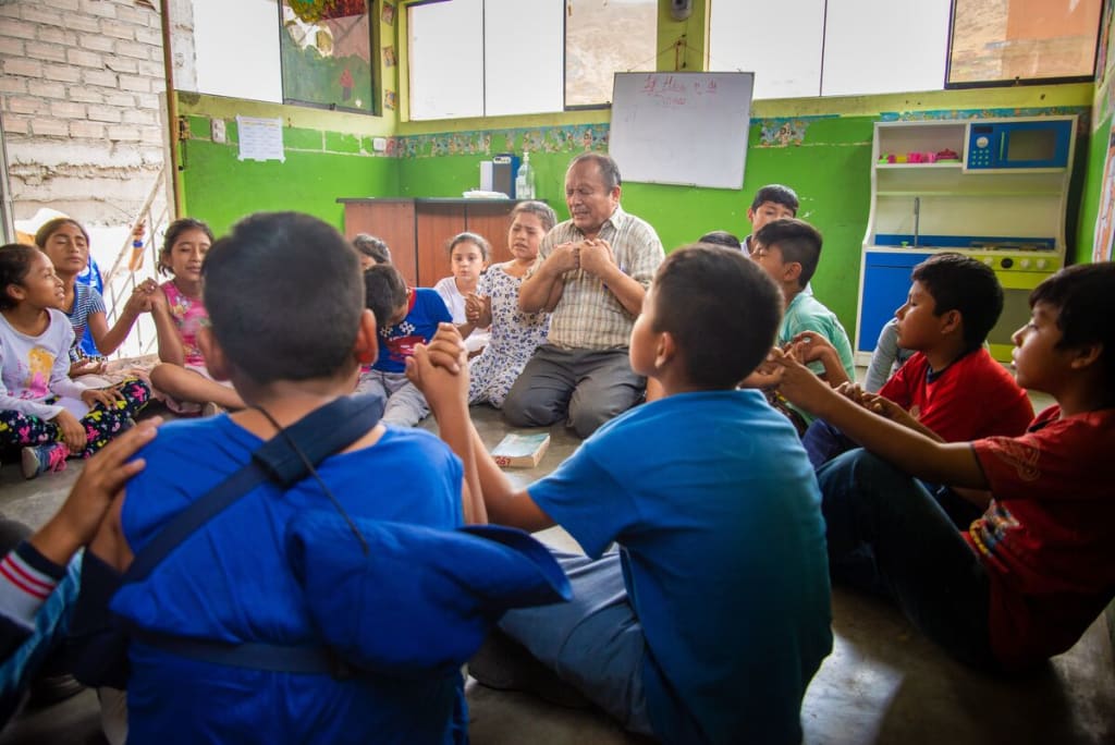 A man prays with a group of children