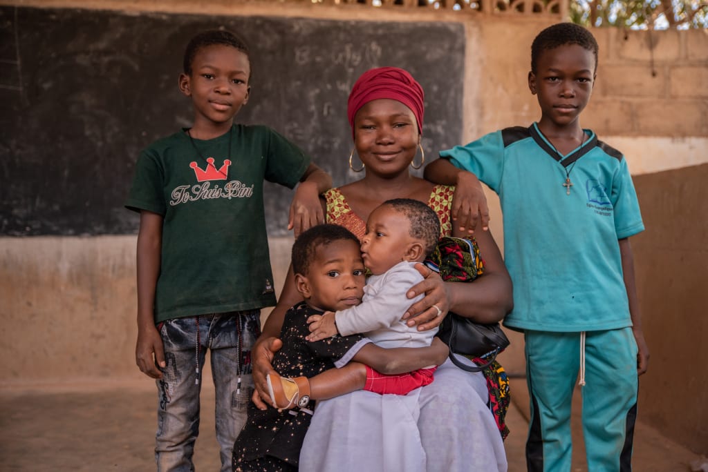 An African woman sitting with her four children smiling and surrounding her
