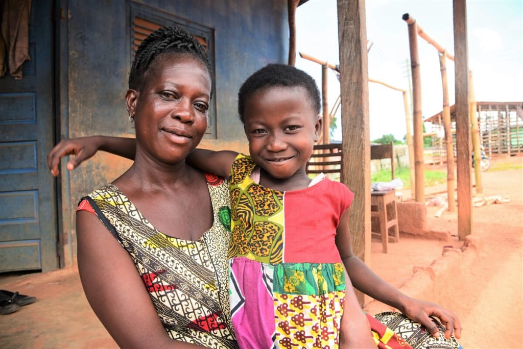 A little girl in a patterned top as her arm around a woman in a printed top.