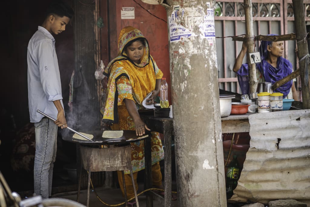 Shanto stands over a grill beside his aunt in their small storefront.