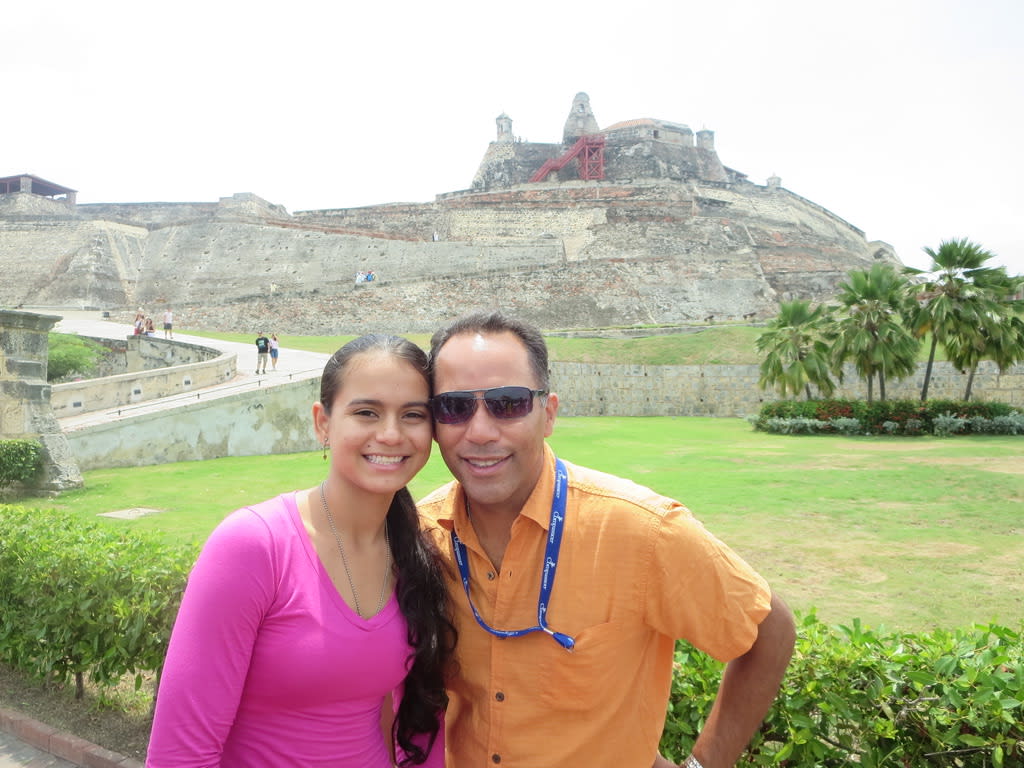 Tim Hague Sr. is wearing an orange shirt and posing for a photo with Elise, a young woman from Colombia who is part of the Compassion program.