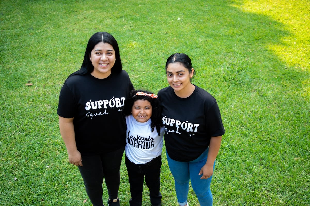Monica (centre director), Valery and Yessenia are smiling and posing for a picture together on the grass.