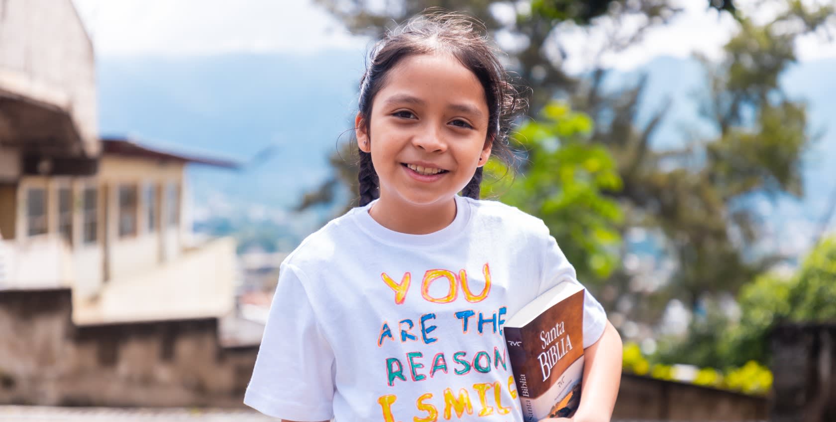 A girl holding a bible and smiling happily