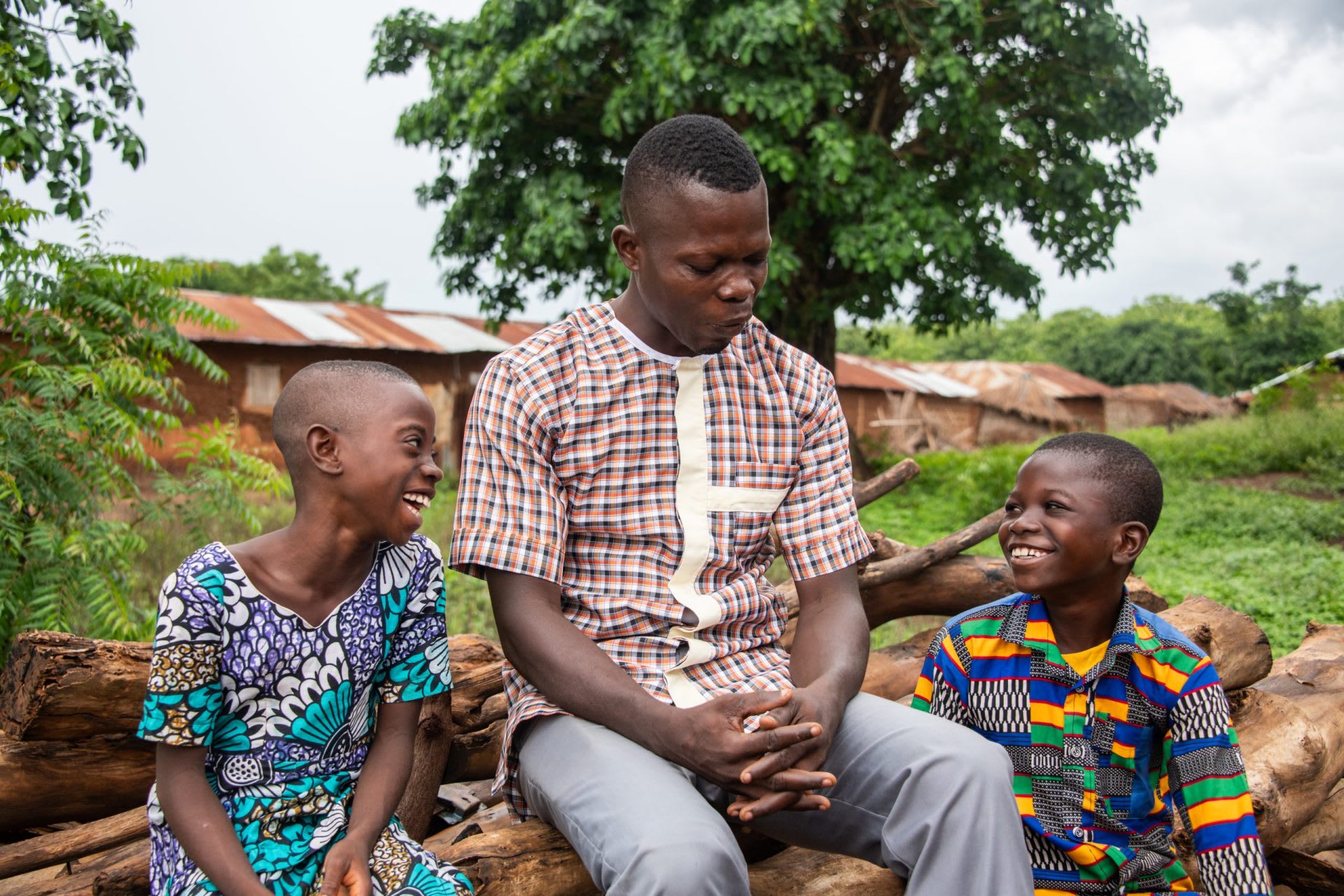 An older black man smiles as he sits beside two happy kids