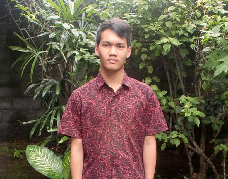 A man in a burgundy shirt looks at the camera