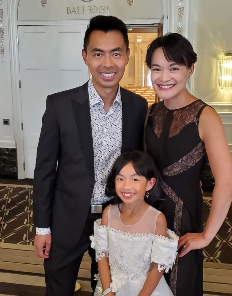 A family of three poses and smiles together.