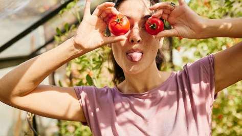 Frau hält sich zwei Tomaten vor die Augen und streckt die Zunge raus