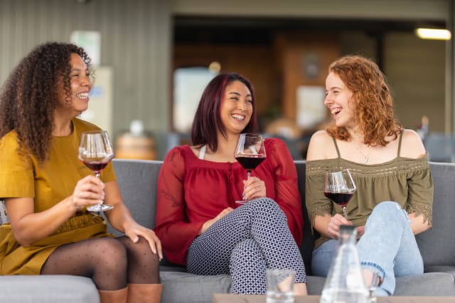 Slide Image. Three women enjoying one of our Big Reds in the gazebo at Compris Vineyard, a green winery in Newberg.