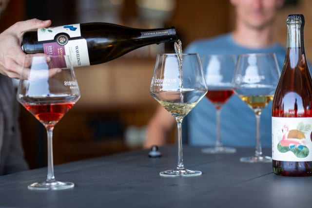 Compris wine glasses on tasting room table with Chardonnay being poured into a glass, a favorite premium wine.