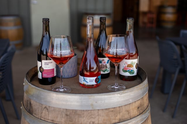 Rosé of Tempranillo, Pinot noir, Chardonnay, and Sparkling Rosé of Pinot noir on top of a wine barrel - some favorite wines of Compris! 