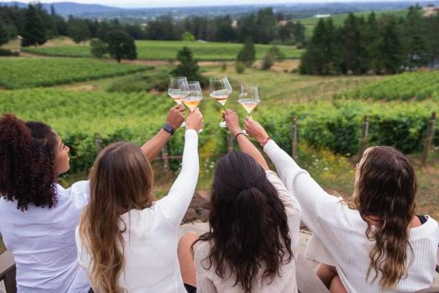 Four people cheering their Rose of Tempranillo with the vineyard view in the background.