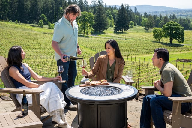 Owner Dru pouring red wine for our guests on the terrace, with the town of Newberg in the distance.