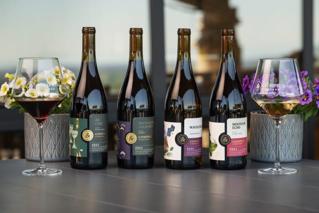 Four wine bottles, Pinot Noir, Syrah, and Chardonnay, premium wine produced at boutique winery Compris Vineyard.