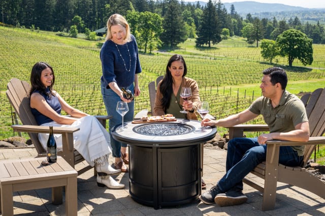 Erin Allen serving Syrah wine to guests seated on the terrace at one of the best wineries in the Willamette Valley.