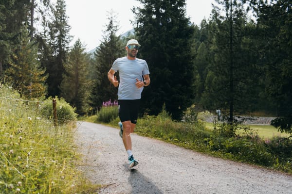 Front view of Patrick running on a paved pin the forest