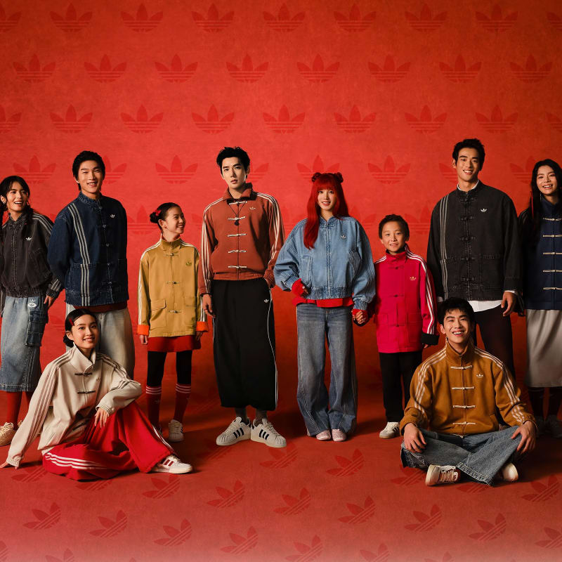 The designers pose in front of a red background
