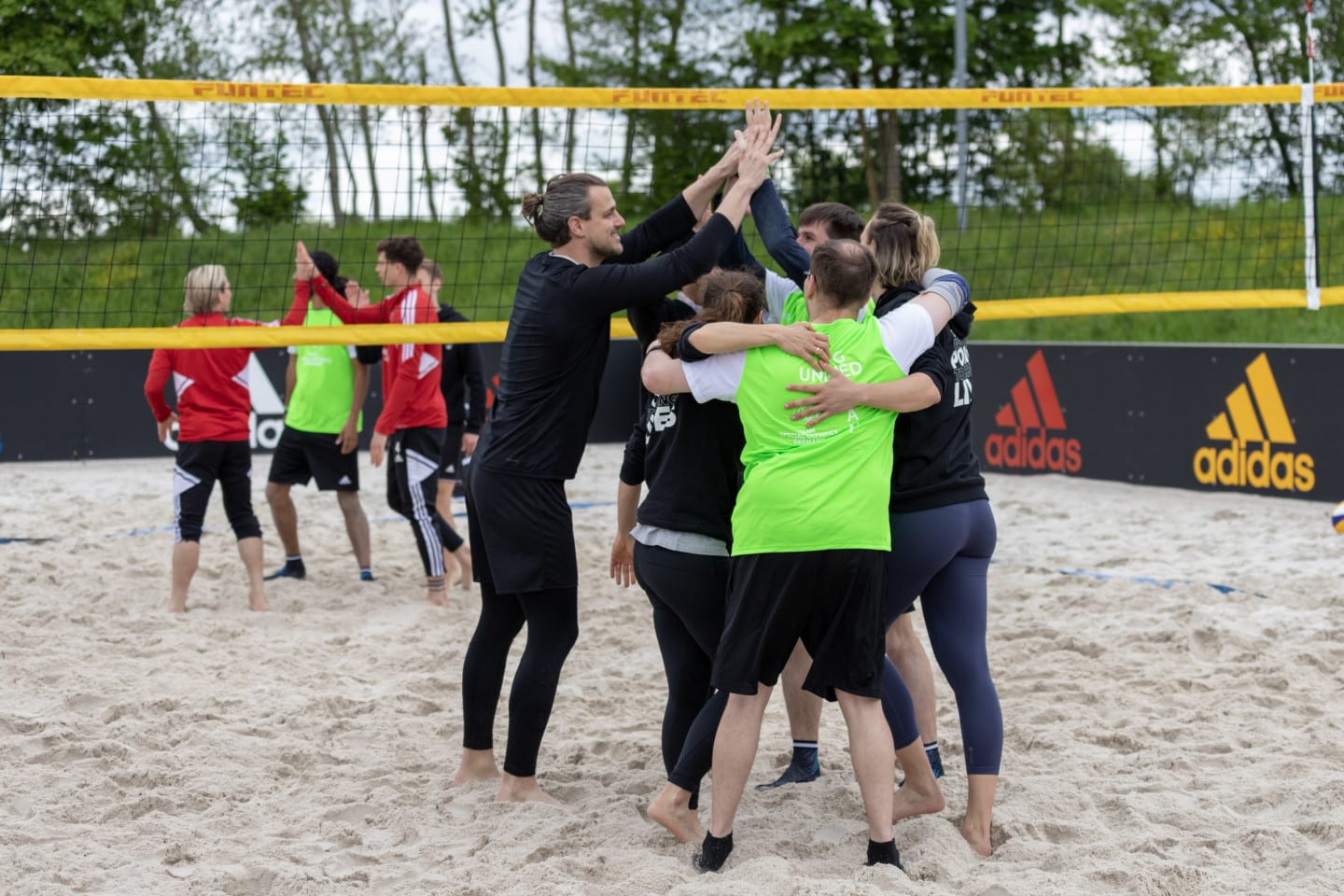 The beach volleyball team playing together with a group of employee volunteers.