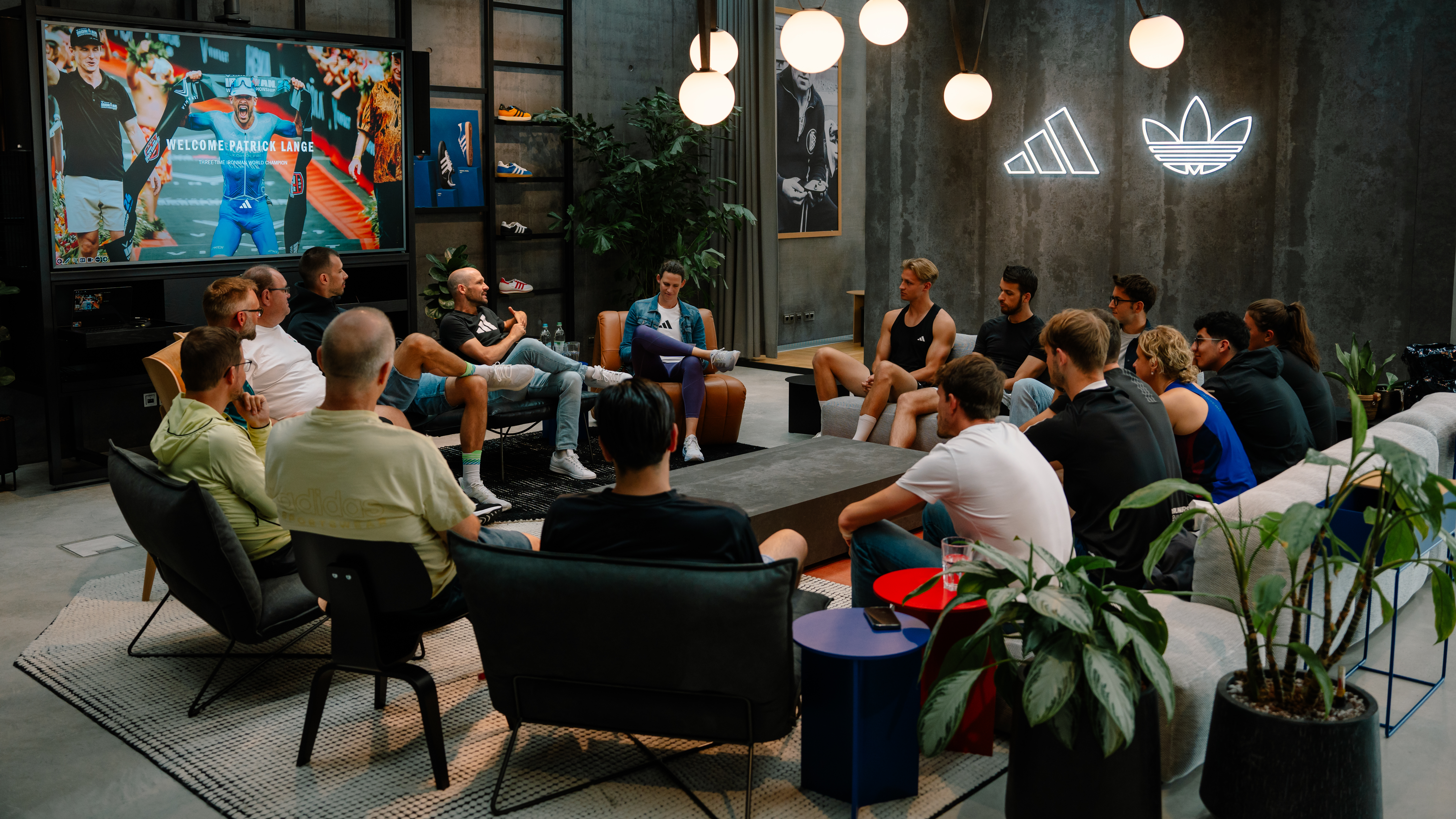 A group of adidas employees sit in lounge chairs in a circle with Patrick Lange for a group interview