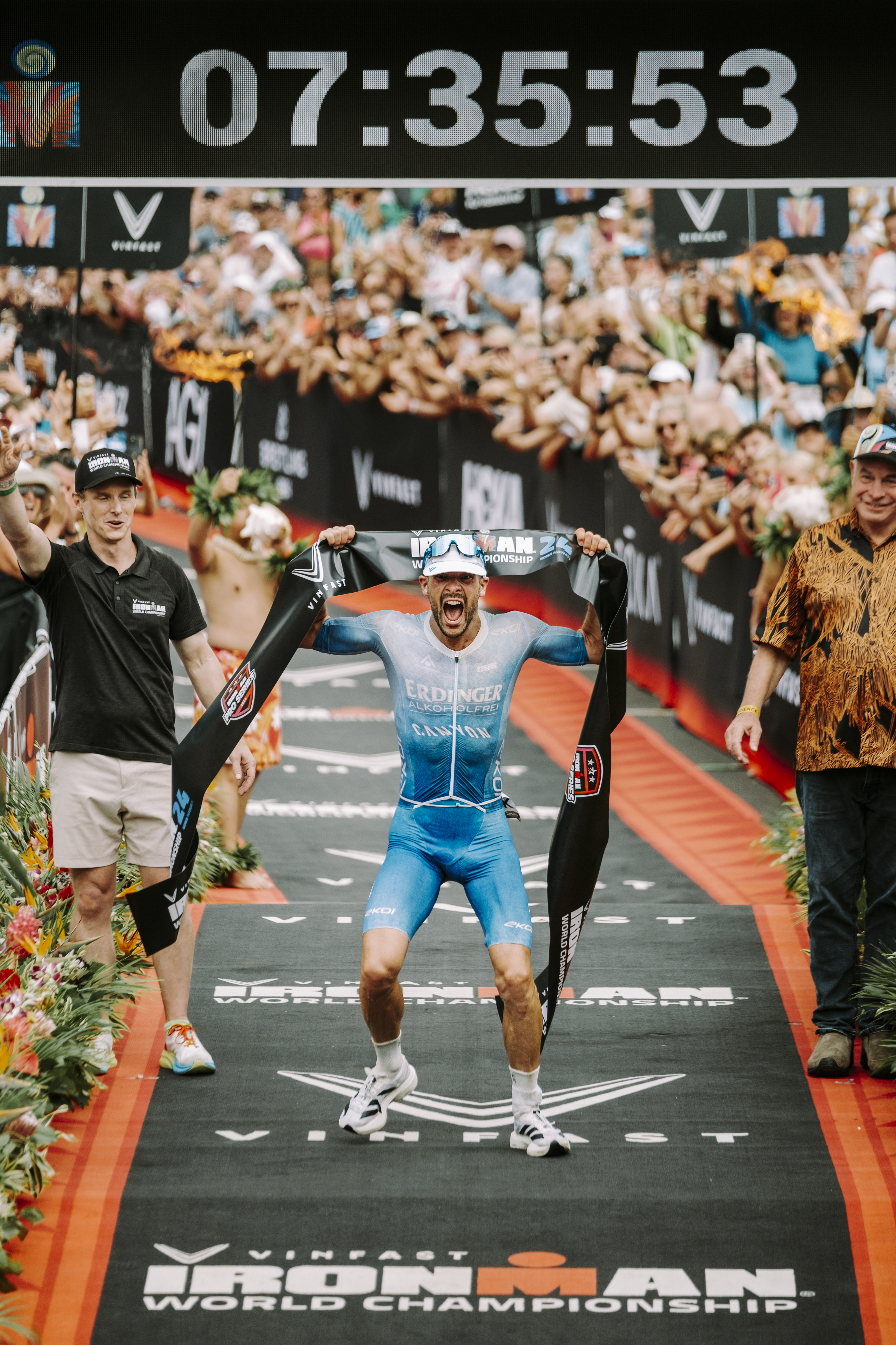 Patrick Lange, the winner holds the finish line tape above his head in Kona, Hawaii