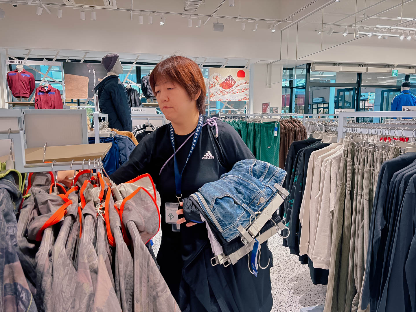 A woman restocks the racks of an adidas store