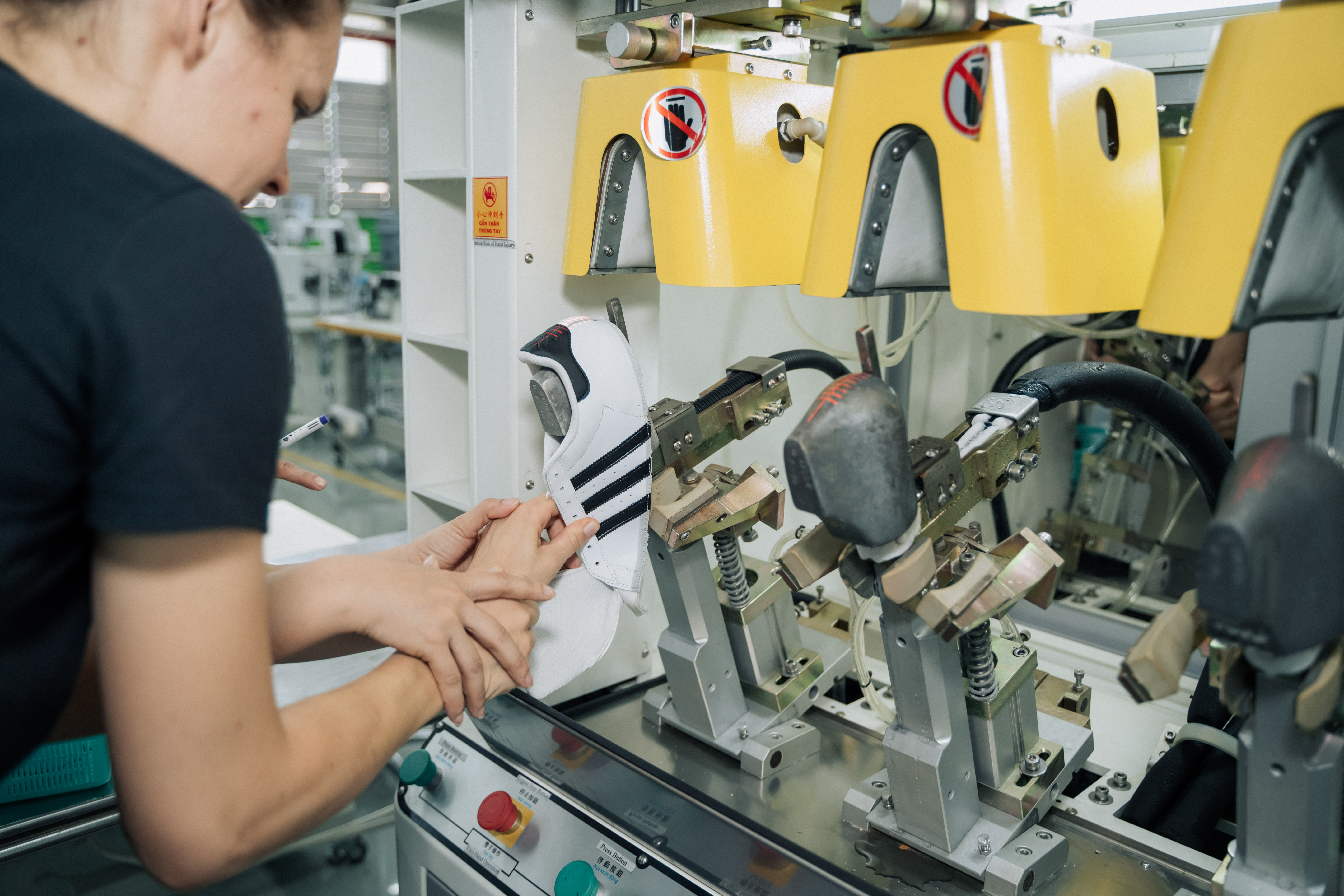 Close-up on one person showing another how to use a machine for shoe construction.