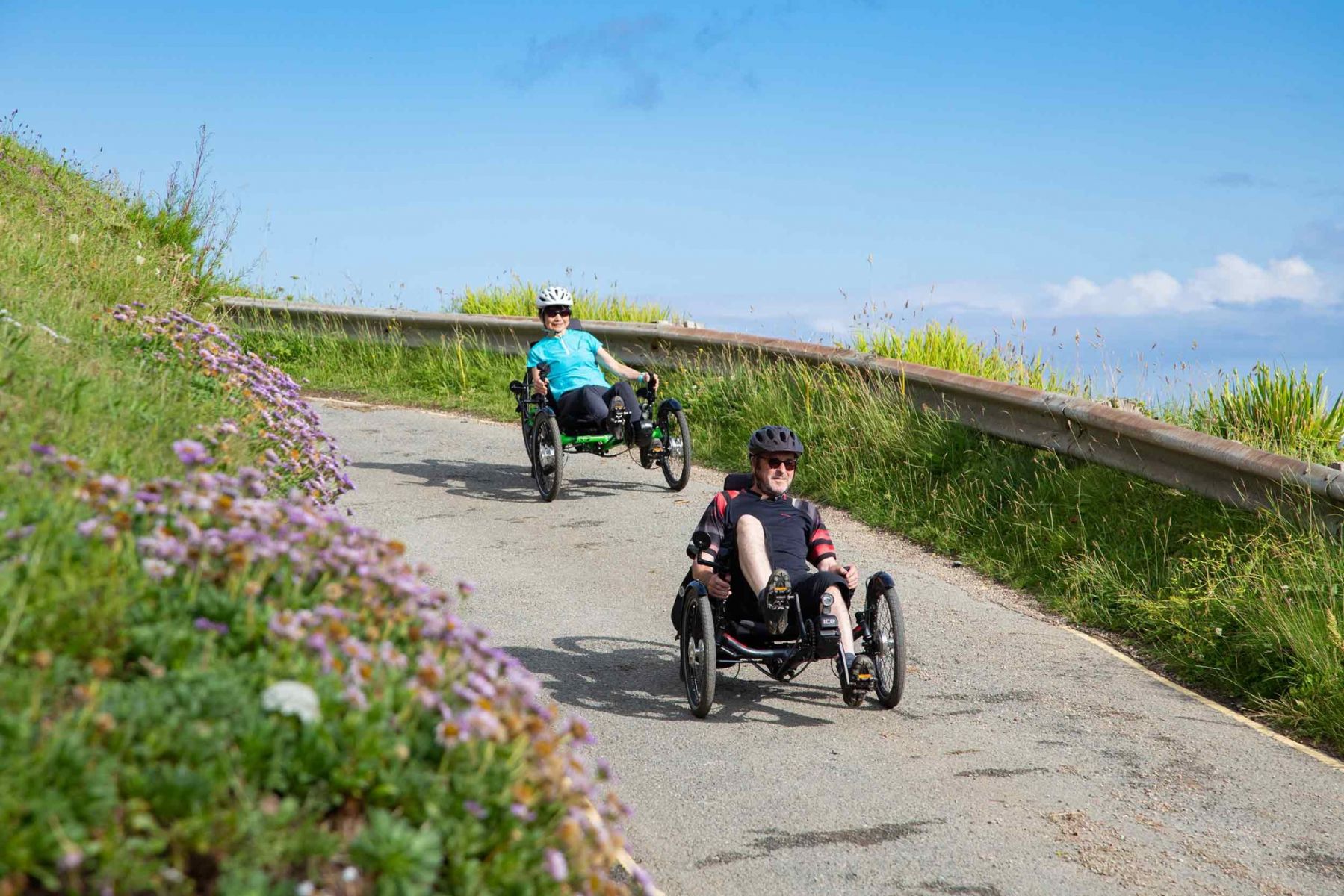 Two trikes going down a downhill path