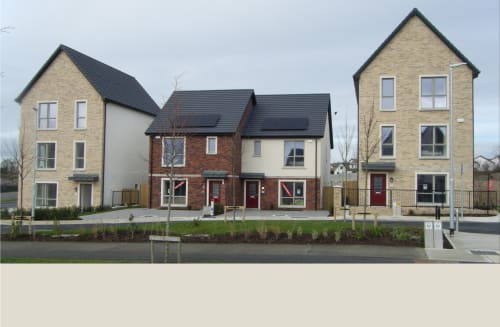 RESIDENTIAL DEVELOPMENT AT RAYNOLDSTOWN VILLAGE Nestled in the southern suburbs of Dundalk, the Raynoldstown Village development presents a thoughtfully designed contemporary interpretation of traditional Irish townhouses. The project seamlessly blends modern living requirements with architectural elements that respect the local context.
The development's varied building heights and façade treatments create an engaging street presence, avoiding monotony while maintaining architectural harmony. Each home benefits from a carefully considered layout that maximizes space and light, with many units featuring full-height windows at the ground level that connect interior living spaces with the outside environment.
This residential scheme successfully delivers contemporary suburban living while establishing a strong sense of place within the expanding Dundalk community, setting a high standard for modern residential development in the region.