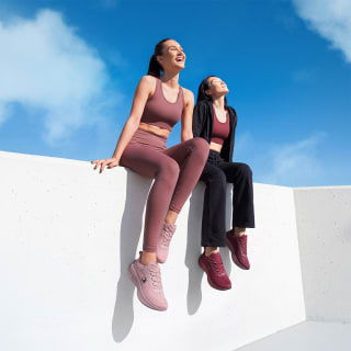 Due ragazze sedute su una muretta che sono vestite con outfit Gymfit Per pilates palestra o yoga