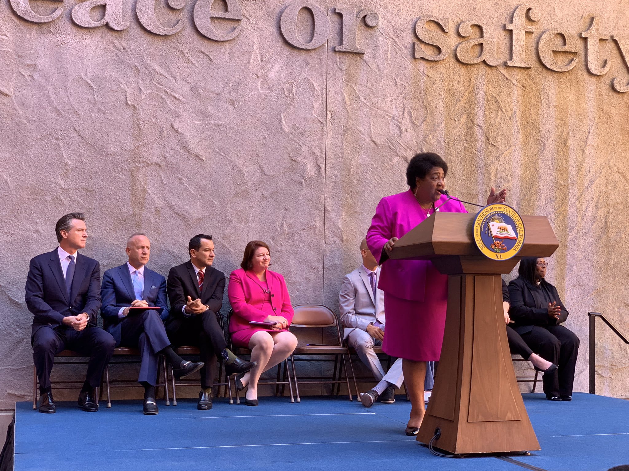 Ngoại trưởng bang California Shirley Weber phát biểu, Thống đốc Gavin Newsom ngồi ngoài cùng bên trái