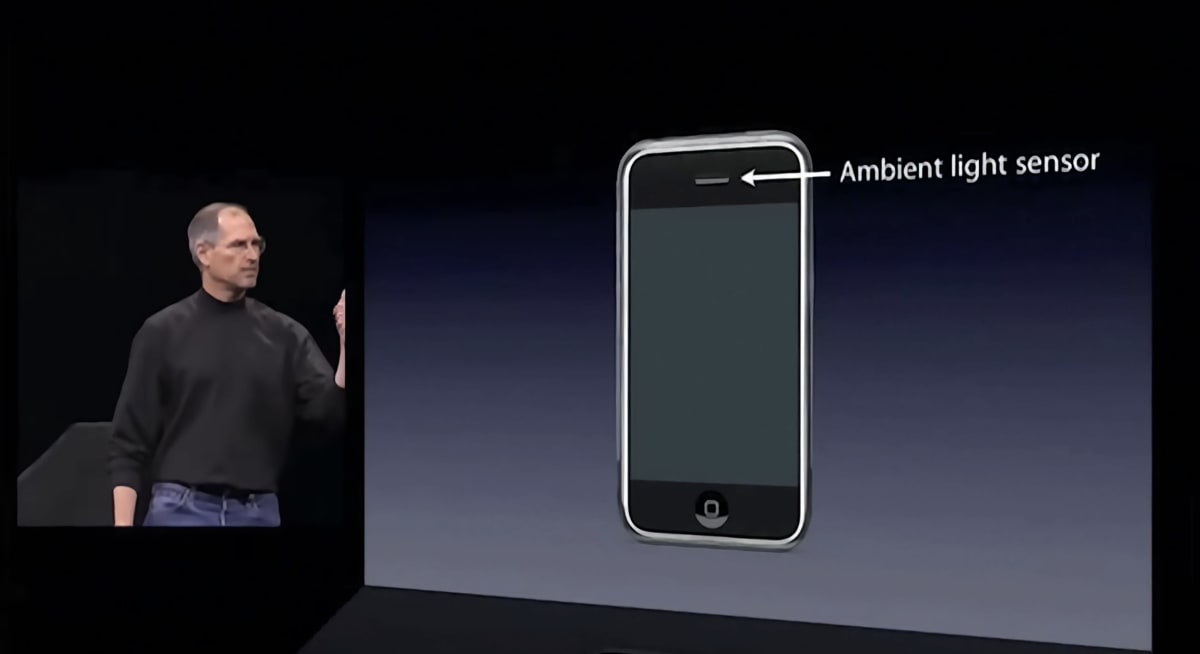Steve Jobs explaining the iPhone’s ambient light sensor, with an arrow pointing to the sensor at the top of the handset.