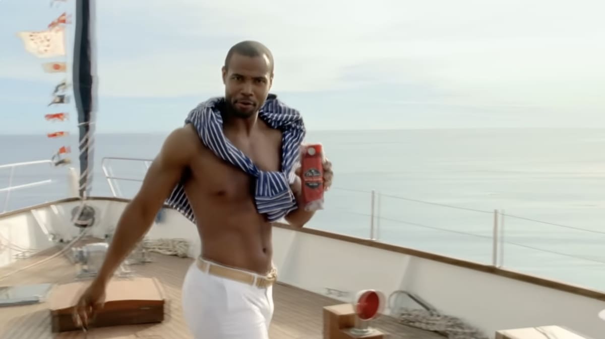 Isaiah Mustafa on the deck of a yacht, shirt draped over his shoulders, holding a bottle of Old Spice body wash, from the ad’s ’You’re on a boat’ sequence.
