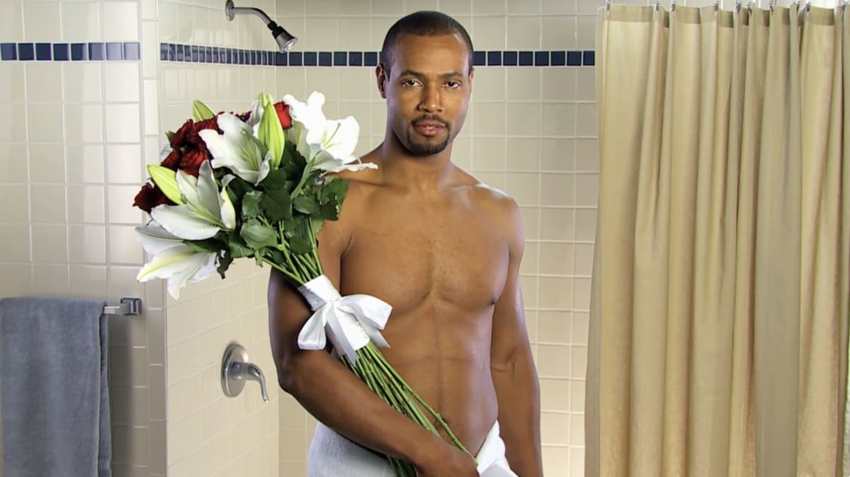 Isaiah Mustafa in the bathroom set, holding a bouquet of red roses and white lilies, from one of the 186 personalized video responses Old Spice filmed to fans and celebrities who mentioned the brand online.