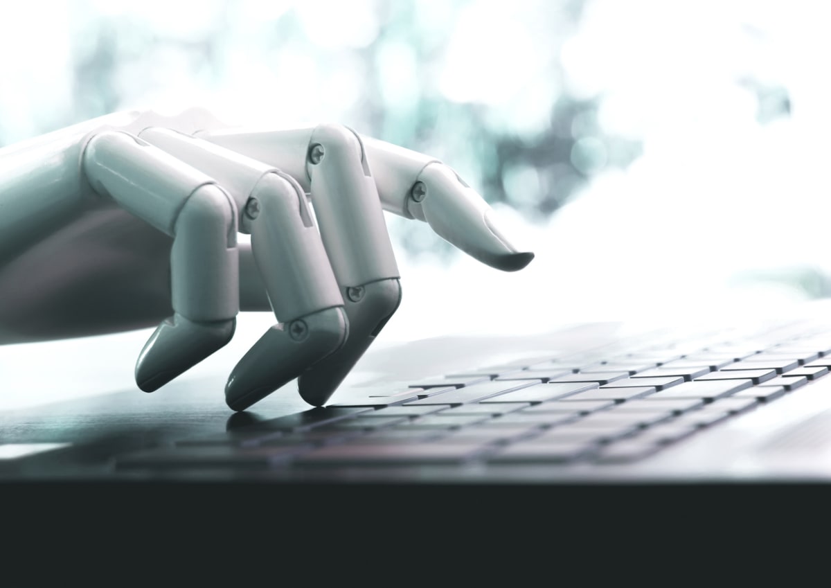 A robot hand types on a keyboard.