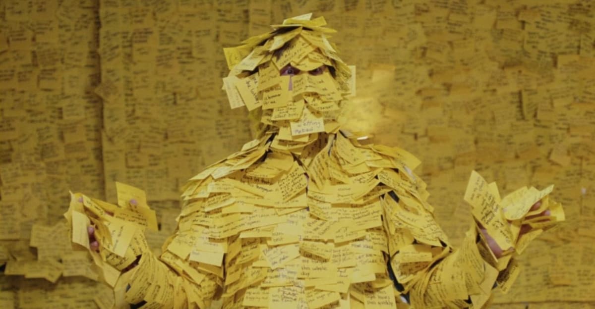 A screenshot from the Bruce Almighty screenshot showing the room covered in post-it notes.